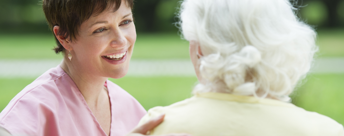 Smiling female CDCP engaging with senior female client outdoors